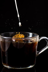 splash of hot instant coffee in a transparent mug on a black background