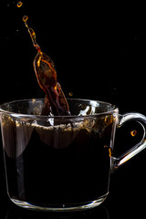 splash of hot instant coffee in a transparent mug on a black background