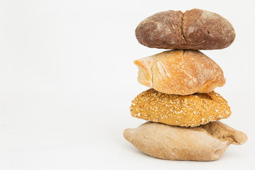 Fototapeta na wymiar Pile of four wheat and rye breads with cereals. Fresh homemade loafs and pastry isolated on white background. Studio shot. Side view. Cooking and baking at home concept