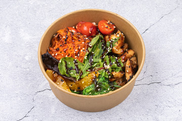 Poke bowl with chicken and vegetables on the white table.