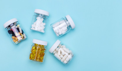Five packs with various pills on a blue background. Health concept. Top view with copy space.