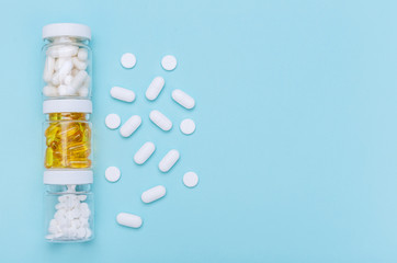 Three packages with various white pills and capcules on a blue background. Health concept. Copy...