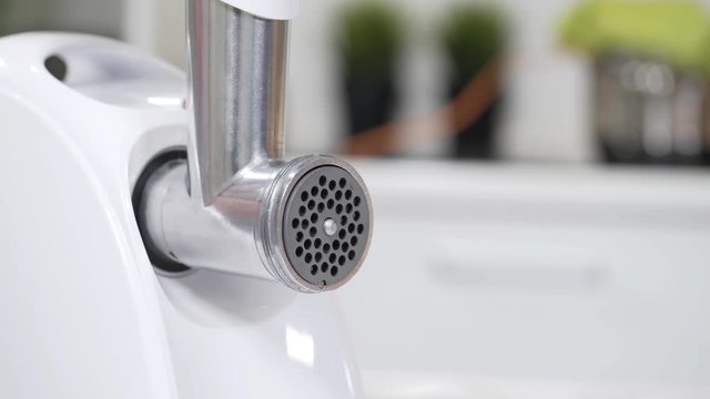 Female hand sets cutting plates in meat grinder for providing quality mince from all types of meat. Electric mincer machine for minced meat per minute, make sausages, mashed berries, squeeze juice.