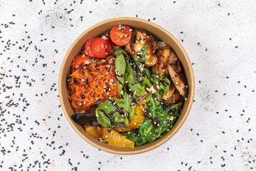 Poke bowl with chicken and vegetables on the white table.