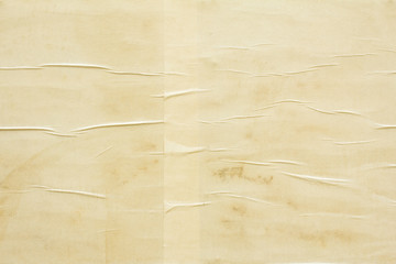 Old crumpled beige brown paper poster glued on billboard. Blank vintage paper with wavy surface texture background.