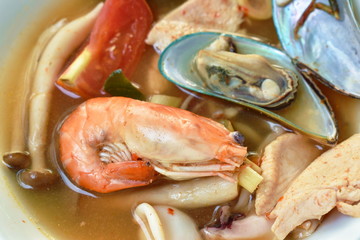 boiled shrimp and chicken with mussel in Thai spicy tom yum soup on bowl