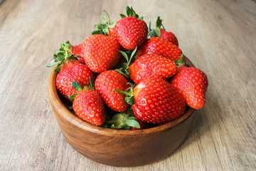 close up image of yummy delicious big red strawberry lie in round wooden plate on light wooden background, antioxidant nutrition,  healthy food concept