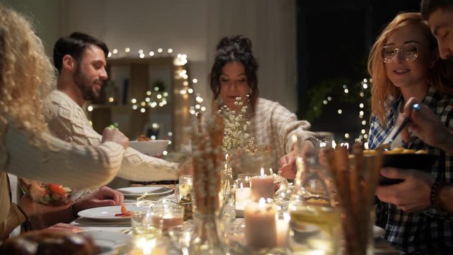 holidays, celebration and people concept - happy smiling friends having christmas dinner and sharing food at home in evening