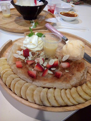 A plate of Roti with Ice Cream Dessert, topping with chopped Strawberry and Banana, includes sliced Almond, condensed milk, Caramel Sauce and Whipped Cream