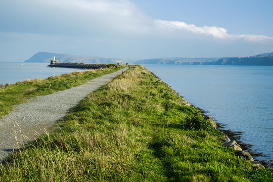 Walking path on the pier towards a lighthouse,  Fishguard, Wales
