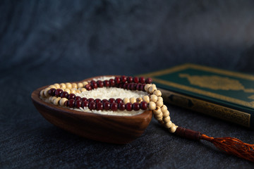 ZAKAT donation for Muslim according to religious principles during the Ramadan month,
concept: rice grain in bow and rosary on black background