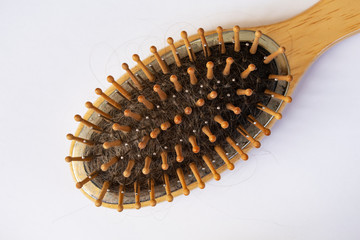 Wooden massage comb with hair on a white background