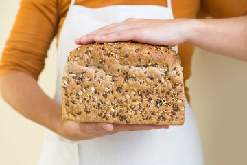 Freshly baked wheat bread with seeds in bakers hands. Closeup of person holding food. Baking or traditional food concept