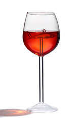 Subject shot of a fantasy wine glass with a long sterm and a crystal shark figure inside. The clear glass with red drink is isolated on the white background.