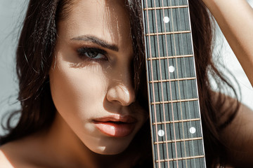 Beautiful woman looking at camera while holding acoustic guitar
