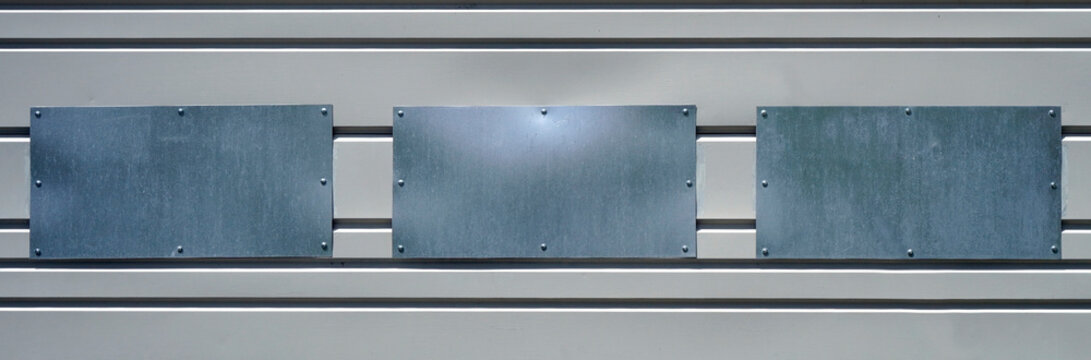 Unusual Abstract Of Three Blank Rectangular Shiny Metal Plates Mounted On Exterior Wall. 