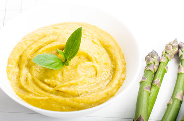 Fresh green asparagus cream soup on white wooden background