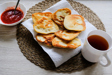 A cup of tea and hash browns on the table.