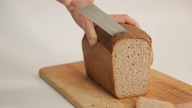 A woman cuts a loaf of bread with a knife. 50p