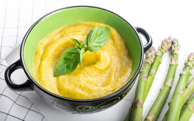 Fresh green asparagus cream soup on white wooden background