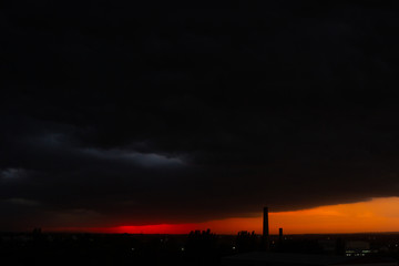 Black thunderclouds at sunset. Bright orange sunset and dark clouds. Storm sky