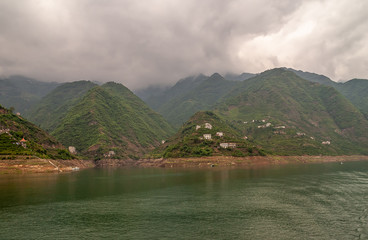 Xinling, China - May 6, 2010: Xiling gorge on Yangtze River. Heavy brown cloudscape above green...