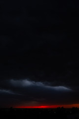 Black thunderclouds at sunset. Bright orange sunset and dark clouds. Storm sky