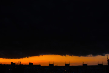 Black thunderclouds at sunset. Bright orange sunset and dark clouds. Storm sky