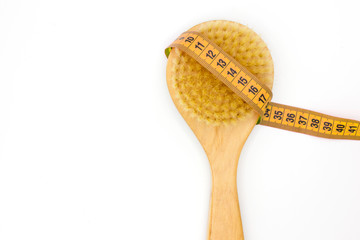 Dry massage eco natural anti cellulite brush with yellow centimeter on white background. Body care home spa. Fitness summer time concept. Space for text. Close up. Top view