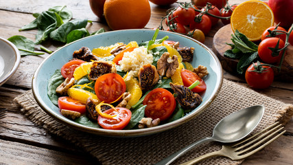 Colorful summer sweet salad with spinach, orange, cherry tomatoes, walnut, figs, quinoa, fresh fruit