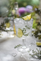Glass with cold iced refreshing summer lemonade with lime and thyme