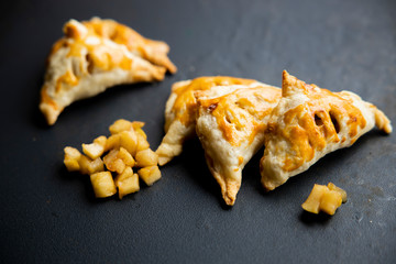 apple turnover on a dark concrete table with apple, horizontal view from above, flatlay, free space