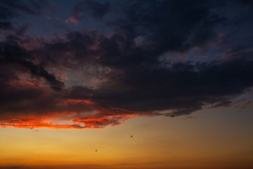 Black thunderclouds at sunset. Bright orange sunset and dark clouds. Storm sky