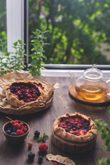 ummer homemade pastry, galette with berries on rustic wooden background