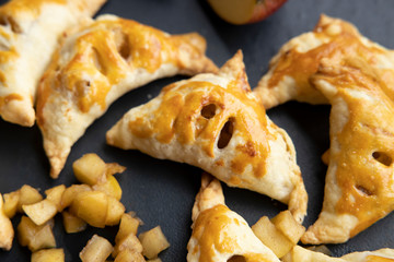 apple turnover on a dark concrete table with apple, horizontal view from above, flatlay, free space