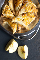 apple turnover on a dark concrete table with apple, horizontal view from above, flatlay, free space
