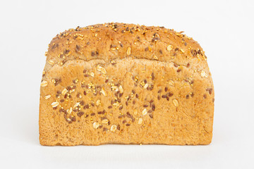 Crusty homemade brick form bread. Tasty whole loaf baked with cereals, oats, seeds isolated on white background. Studio shot. Side view. Cooking and baking at home concept