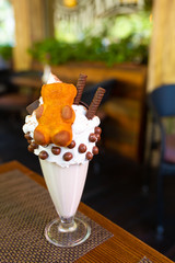 Cool milkshake with cookies and chocolate balls. Milkshake in a glass beaker on a table on a street platform in a cafe. Refreshing summer drinks