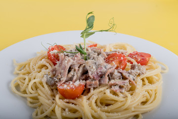 Spaghetti cooked pasta with ingredients on a yellow background. Colorful top and closeup view