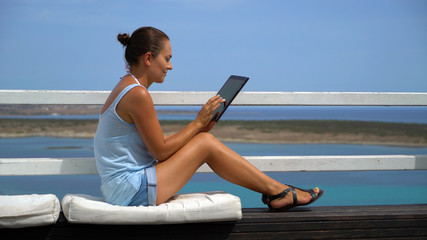 Relaxed and cheerful work and vacation outdoor portrait of happy young woman using tablet