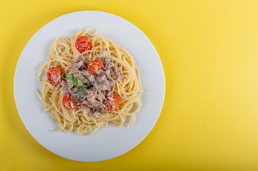 Spaghetti cooked pasta with ingredients on a yellow background. Colorful top and closeup view
