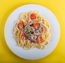 Spaghetti cooked pasta with ingredients on a yellow background. Colorful top and closeup view