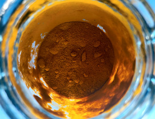 Orange turmeric powder in glass cup, bowl with ingredient close up. colored granules in transparent...