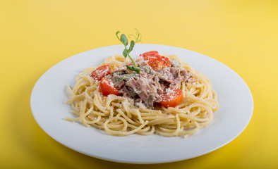 Spaghetti cooked pasta with ingredients on a yellow background. Colorful top and closeup view
