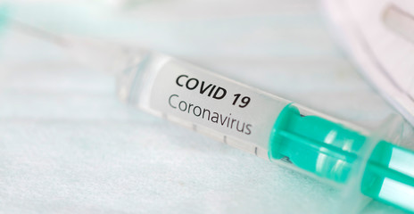 Close-up of syringe with vaccine against corona and mouth nose mask