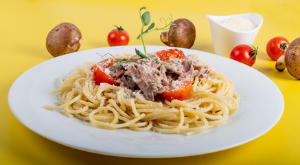 Spaghetti cooked pasta with ingredients on a yellow background. Colorful top and closeup view