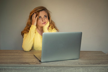 Young woman is working online. Girl with laptop. Smiling woman in  a yellow cardigan