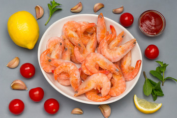 Frozen shrimp and ice in white bowl. Rice noodles, lemon, mint garlic, tomato sauce.