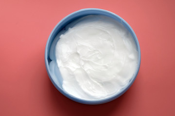 White cream in a round container top view. Body cream in a box on a pink background. Face and body skin care, cosmetic products.