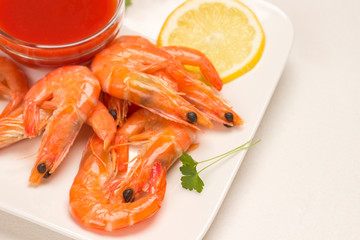 Shrimps with lemon and tomato sauce and herbs in plate.